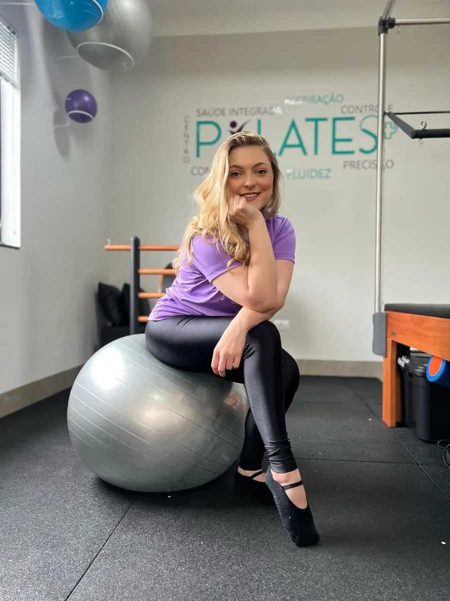 Fernanda Ferrari Godoi, fisioterapeuta, sentada em bola de pilates no studio da Clínica Vivaz
